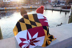 two people wrapped in the crabcakes & cannabis flag overlooking the water in annapolis